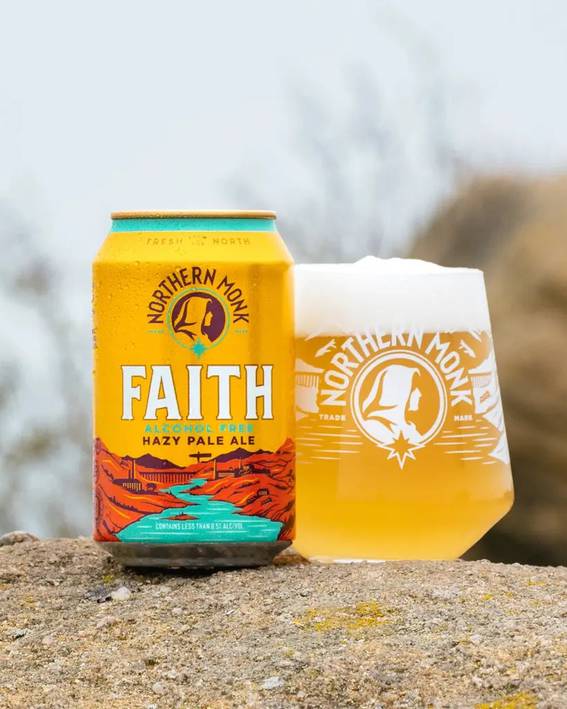 Northern Monk Faith alcohol free hazy pale ale can beside a full branded glass outdoors